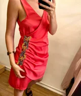 Vestido corto color coral, con escote cruzado, breteles finos y detalle de bordado con piedras en el lateral.