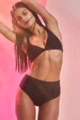 Conjunto de bikini negro confeccionado en lycra brillante. El corpiño es de estilo triángulo con breteles anchos fijos y pinzas para dar volumen. La bombacha es de tiro medio.
