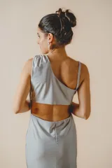 Vestido largo fit al cuerpo color plateado con un solo hombro, diseño fruncido en el lateral, tajo lateral en la falda y abertura en la espalda.