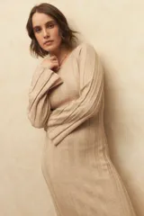 Vestido midi de punto acanalado en color gris, con mangas largas acampanadas y aberturas laterales en el ruedo. Presenta un diseño ajustado al cuerpo.