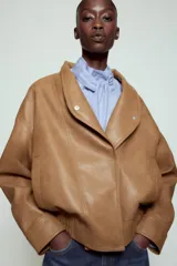 Chaqueta bomber ZW Collection confeccionada en tejido efecto piel de color marrón. Cuenta con cuello subido, manga larga con puño y botón a presión, bolsillos delanteros y bajo recto elástico. Cierre frontal cruzado con botones a presión.