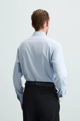 Camisa blanca de manga larga con cuello italiano y cierre frontal de botonadura. Corte regular fit.