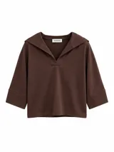 Remera de tejido suave color beige, con cuello en V solapado y capucha integrada, de mangas tres cuartos con puños amplios.