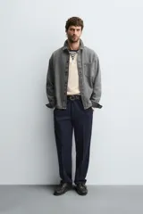 Camisa de denim de algodón, color gris oscuro lavado, de corte holgado (boxy fit). Presenta cuello solapa, manga larga con puño abotonado, bolsillo de plastrón en el pecho y cierre frontal con botones.