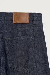 Jeans de corte recto en denim azul oscuro, con mezcla de algodón y cáñamo sin lavados. Presenta diseño de cinco bolsillos, tiro medio y cierre frontal con cremallera y botón.