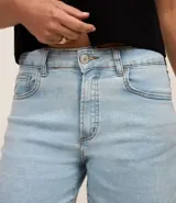 Short de jean celeste, con cintura media, trabillas, cierre con botón y cremallera, y bolsillos delanteros y traseros.