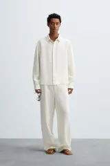 Camisa de corte relajado confeccionada en tejido de cáñamo, color blanco. Presenta cuello de solapa, manga larga con puños abotonados y cierre frontal de botonadura.