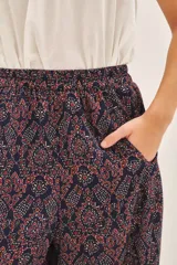 Pantalón tipo babucha o pirata de viscosa, color azul marino con estampado en tonos rojizos y blancos. Presenta un corte amplio, bolsillos laterales y cintura elástica.