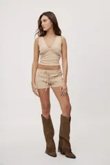 Short de tiro bajo con textura efecto gamuza color beige, bolsillos delanteros y detalle de cordones entrecruzados en la parte frontal.
