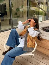 Chaleco de piel sintética en color gris, con diseño reversible. El interior presenta un forro de tela color mostaza con estampado floral bordado. Posee un corte holgado y sin mangas.