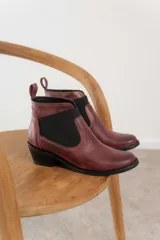 Botín negro de cuero con elásticos laterales, taco bajo y tirador trasero.