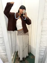 Falda larga de algodón con diseño de paneles en tonos beige y marrón, con costuras visibles y detalles de flecos en el ruedo.