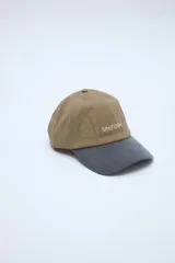 Gorra de visera curva combinada, con cuerpo marrón tostado, visera gris y detalle de bordado con la palabra 'UNIFORM' en el frente.