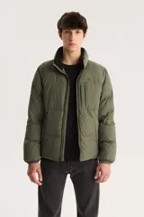 Campera puffer verde militar con cuello alto, cierre frontal con cremallera y bolsillo pequeño en el pecho.