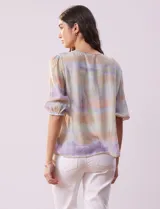 Blusa de gasa estampada con cuello a la base, escote en V plisado y lazo de ajuste. Delantera con detalles en puntilla y manga corta con puño fruncido.