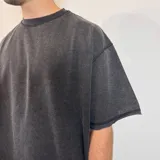 Remera de corte oversize en color verde oliva con efecto lavado, confeccionada en tela rústica pesada, con cuello redondo y bordes sin costura.