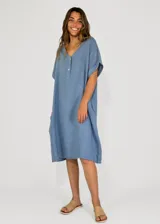 Vestido midi de lino color beige, con cuello en V, cierre frontal parcial con botones y mangas cortas con dobladillo.