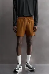 Short deportivo de entrenamiento en tejido técnico ligero y elástico, con cintura elástica ajustable mediante cordón. Presenta bolsillos frontales, un bolsillo trasero con cierre y aberturas laterales en el bajo. Incluye un pequeño logo estampado en la pernera.
