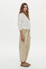 Jean de corte barrel color beige, con diseño estructurado de perneras curvas y pinzas.