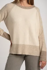 Sweater de punto con diseño color block en tonos beige y arena, de cuello redondo, manga larga raglán y puños y ruedo acanalados.