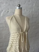 Top tejido de hilo color crudo, con escote halter y espalda descubierta. Se ata en el cuello y en la cintura.