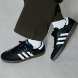 Championes Adidas Samba Og negros con las tres tiras blancas y suela marrón.