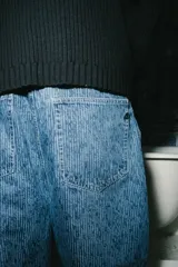 Jean de corte baggy con diseño de rayas verticales finas en denim azul, tiro alto y bolsillos laterales.