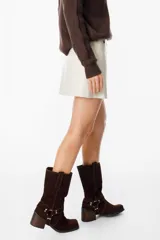 Mini falda tipo cruzada confeccionada en cuero, con detalle de cintura con tachas metálicas.