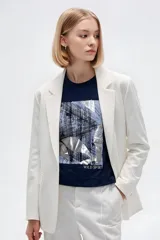 Remera de manga corta de algodón en color blanco, con cuello redondo y diseño holgado. Presenta un estampado frontal con detalle de acabado metálico (foil).