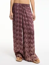 Pantalón de viscosa con estampado abstracto en tonos marrones y morados, de tiro medio-alto, pretina elástica, bolsillos laterales y corte amplio.