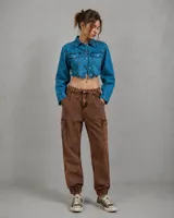 Pantalón cargo de jean color marrón con efecto desteñido, bolsillos laterales con solapa, cintura con presillas y puños elásticos en los tobillos.