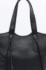 Cartera tipo tote de diseño amplio y textura símil cuero, con asas trenzadas y terminaciones artesanales.