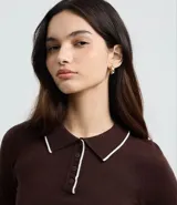 Blusa de punto color blanco con cuello polo, manga larga y detalles de ribete en contraste color negro en el cuello, puños y ruedo. Confeccionada en mezcla de viscosa, poliéster y poliamida.