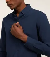 Camisa blanca de corte regular, confeccionada en tejido Oxford de algodón, con cuello inglés, mangas largas y cierre frontal abotonado.