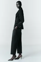 Pantalón de corte recto y largo tobillero, con tiro medio. Presenta bolsillos frontales, falsos bolsillos traseros de vivo y cierre frontal con cremallera, botón interior y ganchos.