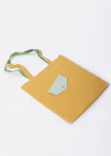 Bolso tote color ocre de material sintético con bolsillo decorativo color celeste y asas dobles con detalle de color verde en el interior.