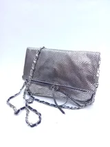 Cartera plateada tipo bandolera con solapa y cierre magnético. Tiene una cadena corta y una cadena larga.