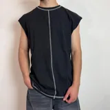 Musculosa de corte oversize color negro, con costuras expuestas en color blanco que recorren el centro y los bordes, aportando un diseño moderno y minimalista.