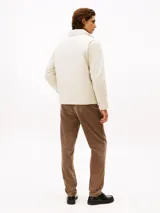 Campera ligera color crema, con cuello alto y cierre frontal de cremallera. Presenta un pequeño logo bordado de Tommy Hilfiger en el pecho.