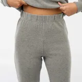Pantalón de corte flare confeccionado en tejido de punto suave color gris, con cintura elástica y ajuste entallado en la parte superior que se ensancha hacia el ruedo.