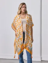Kimono tejido con estampado abstracto en tonos azules, blancos y violetas. Tiene terminación de ruedo con borlas.
