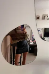 Minifalda negra de cuero sintético con corte campana y costuras decorativas en hilo blanco.