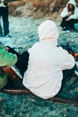 Hoodie de corte oversize color rosado, con capucha, mangas largas y estampa trasera con la inscripción "Glassy Waves Surf Company".
