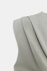 Top de punto negro con cuello redondo, manga sisa, hombreras y detalle de pliegues en la parte delantera.