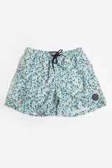 Short de baño celeste con estampado de hojas pequeñas en tonos verdes y blancos. Cuenta con cintura elástica con cordón ajustable, bolsillos laterales y un parche circular con logo en la parte inferior.