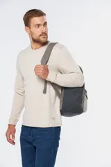 Mochila azul de lona tipo canvas con bolsillo frontal y logo de la marca en etiqueta de cuero.