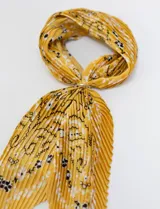 Bandana de satén plisado color amarillo con estampado de flores blancas y negras. Incluye un anillo metálico plateado para ajustar.