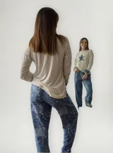 Pijama compuesto por una remera de manga larga color champagne con estampa de estrella azul en el frente y un pantalón de jean con diseño de parches y estampado de estrellas.