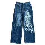 Pantalón de jean azul con estampado de un dragón blanco en la pierna derecha, corte recto y tiro bajo.