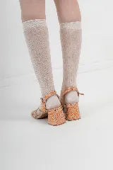 Sandalias de tacón bajo con diseño de tiras finas cruzadas en el empeine y cierre de hebilla en el tobillo. Presentan una puntera cuadrada y acabado con textura efecto reptil en tonos metalizados.